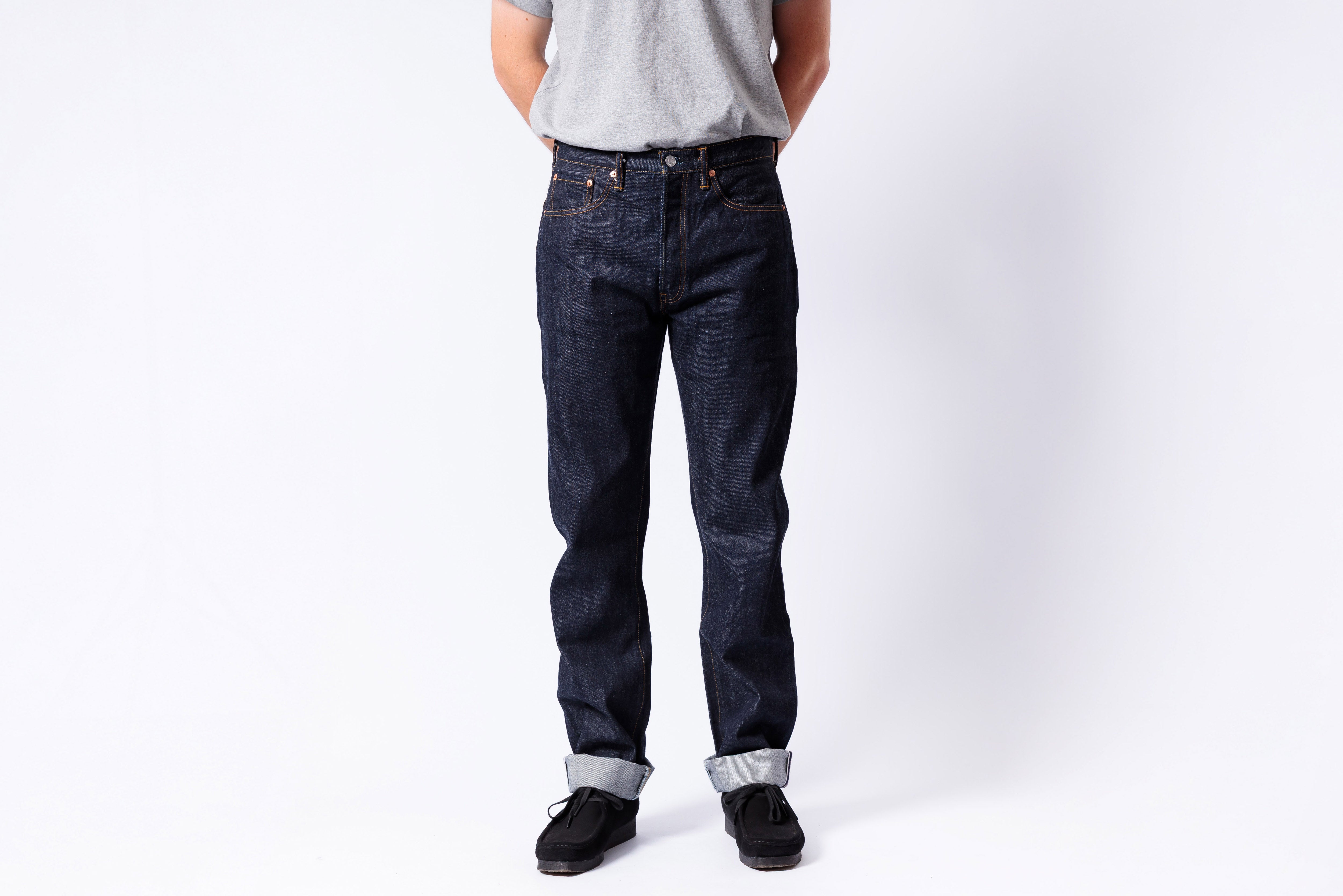 Person wearing dark blue jeans and a light gray shirt on a white background