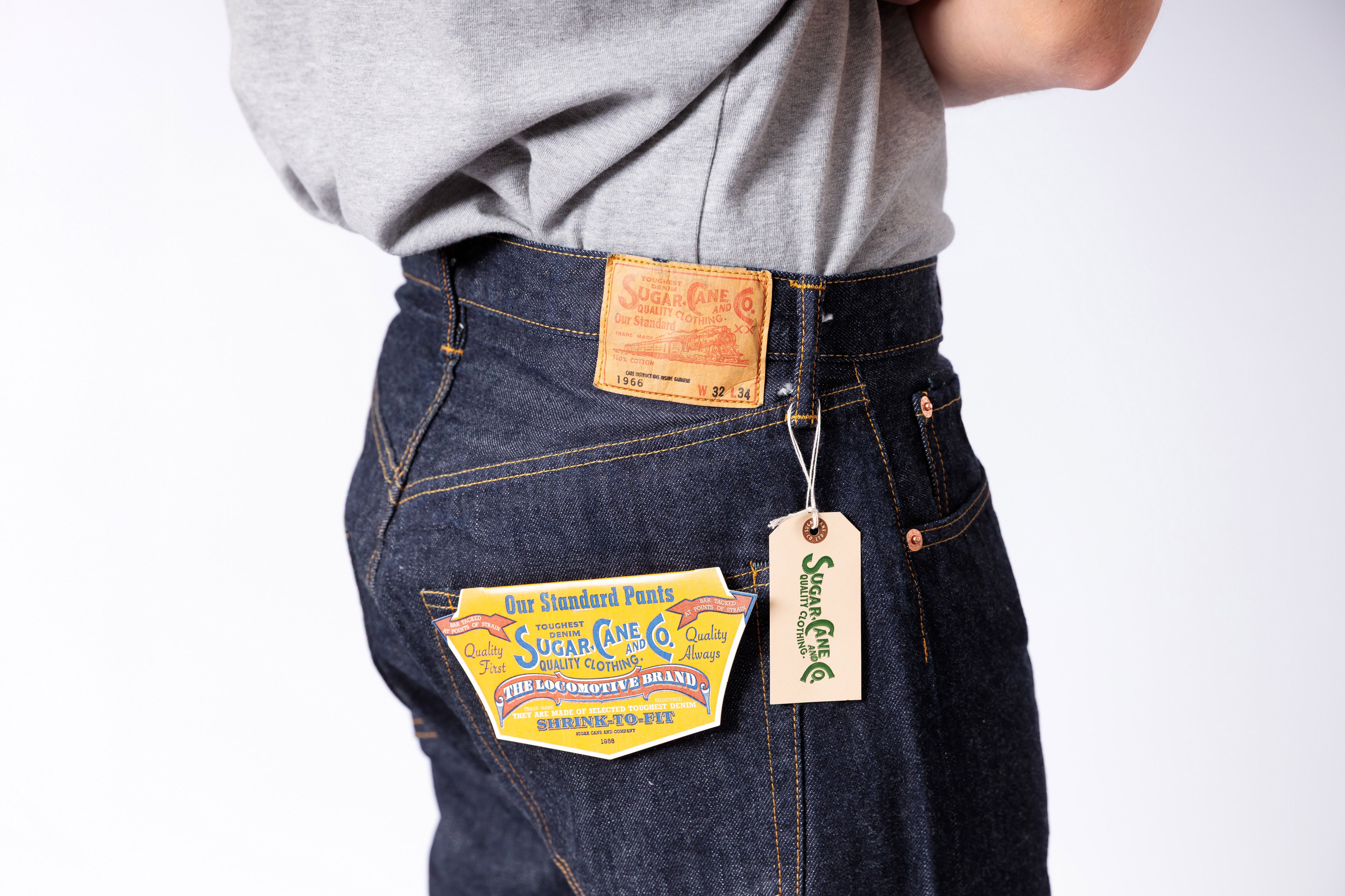 Person wearing dark blue jeans with visible brand tags on a white background