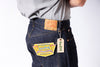 Person wearing dark blue jeans with visible brand tags on a white background