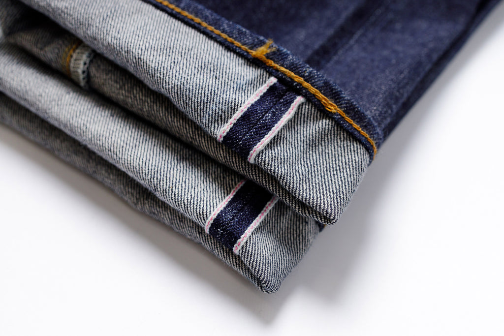 Stack of folded denim jeans on a white background