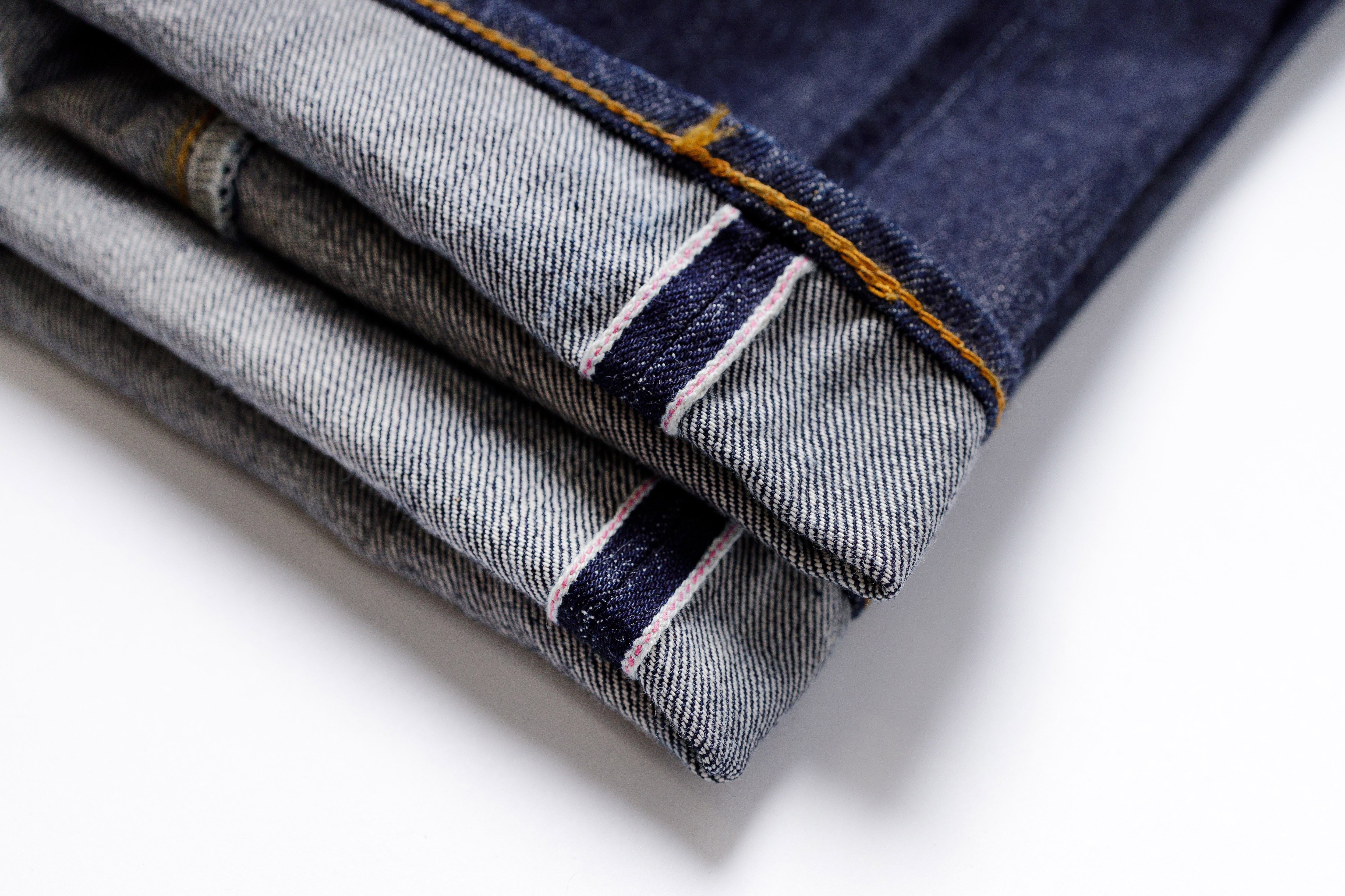 Stack of folded denim jeans on a white background