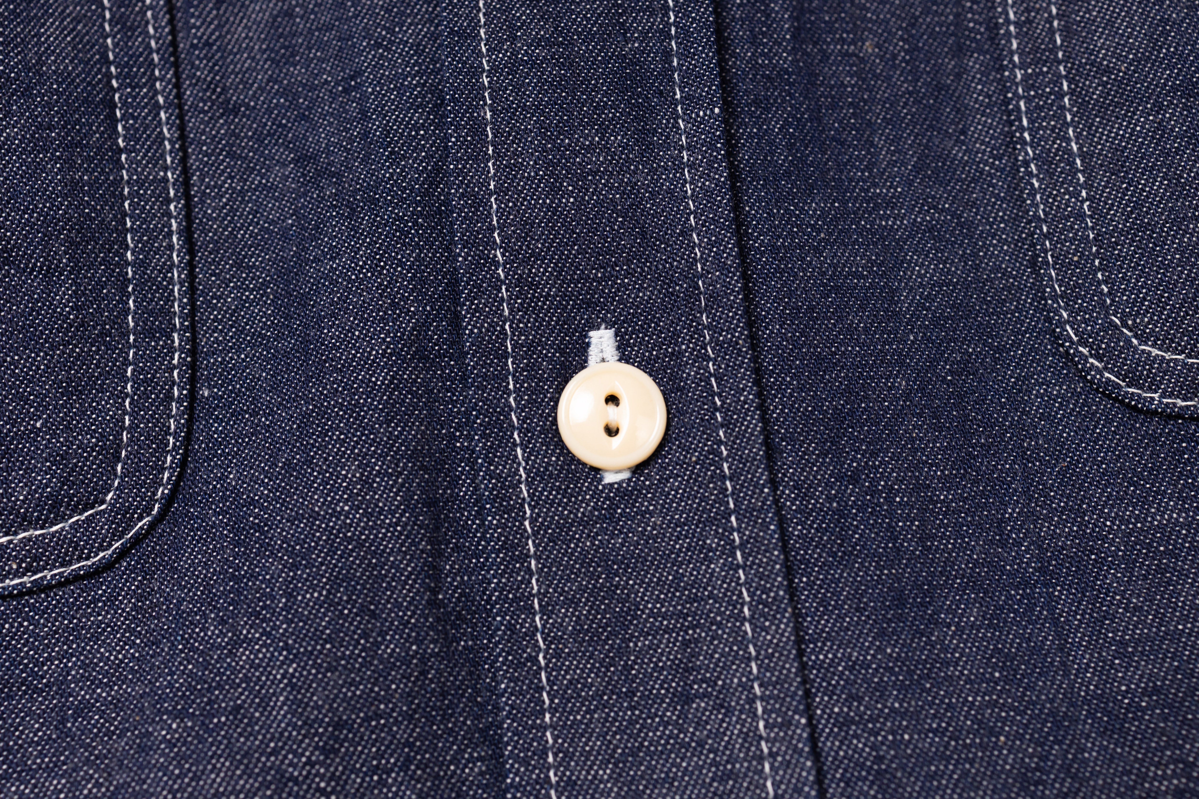 Close-up of a button on a dark denim fabric