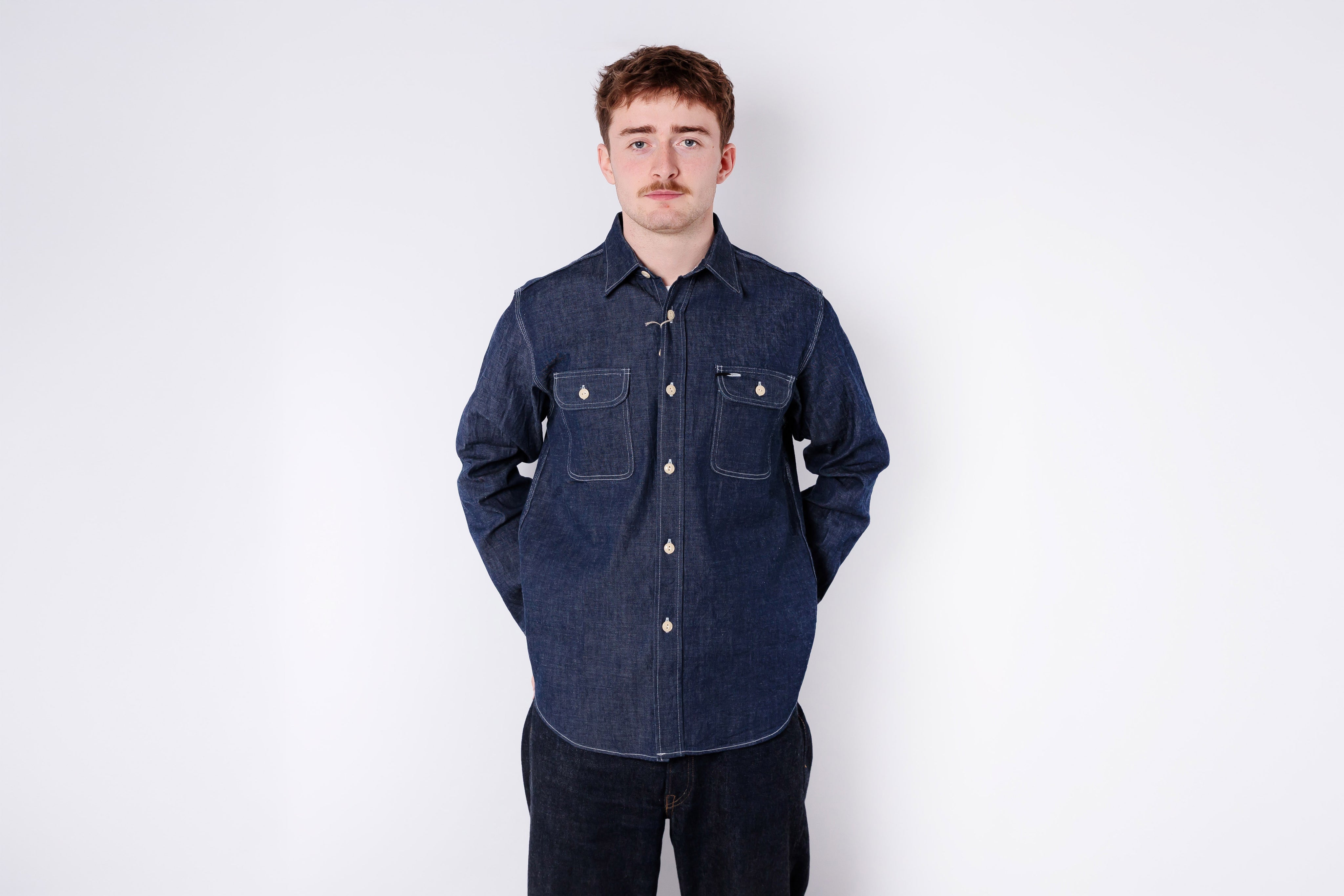 Man wearing a dark blue denim shirt against a white background