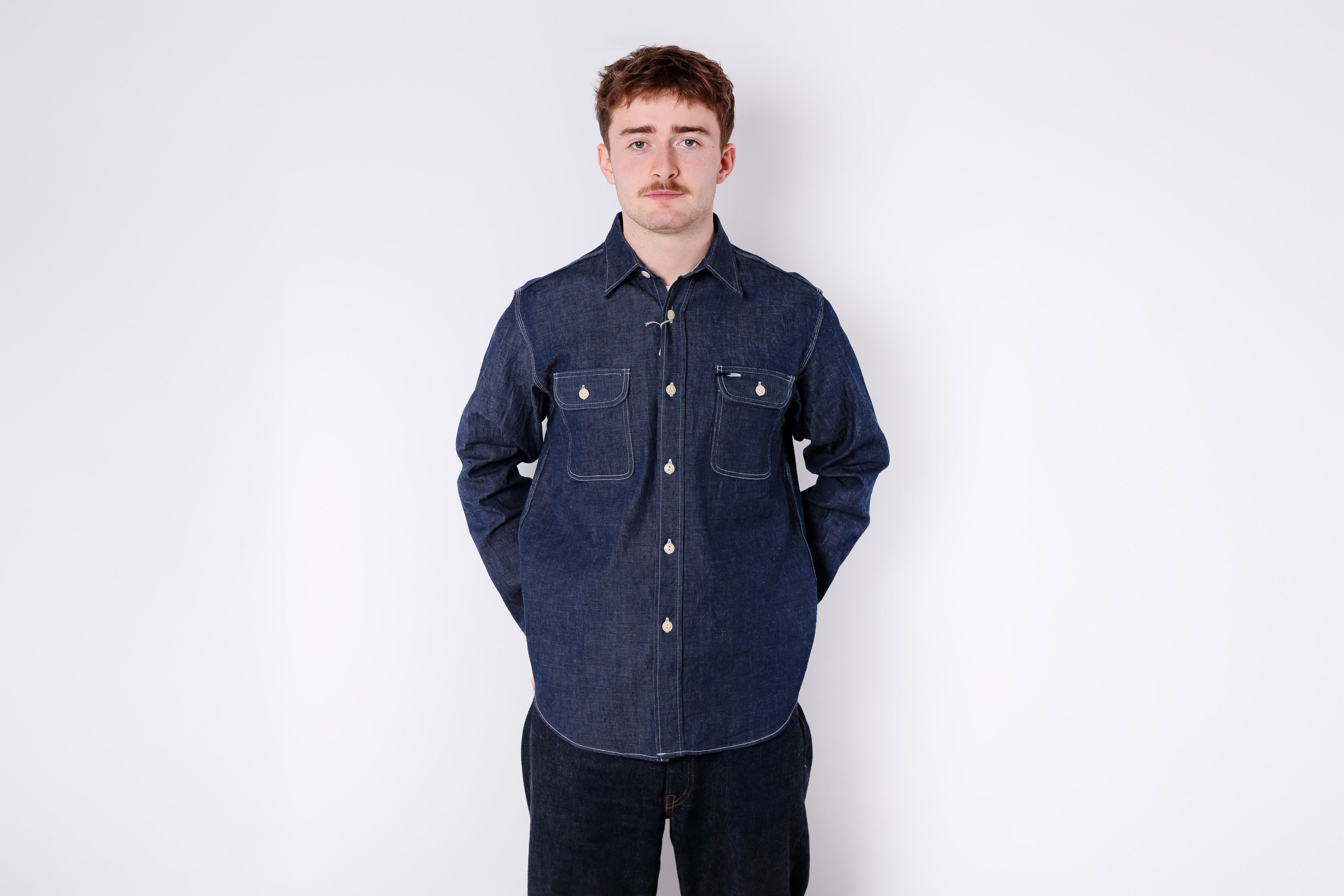 Man wearing a dark blue denim shirt against a white background