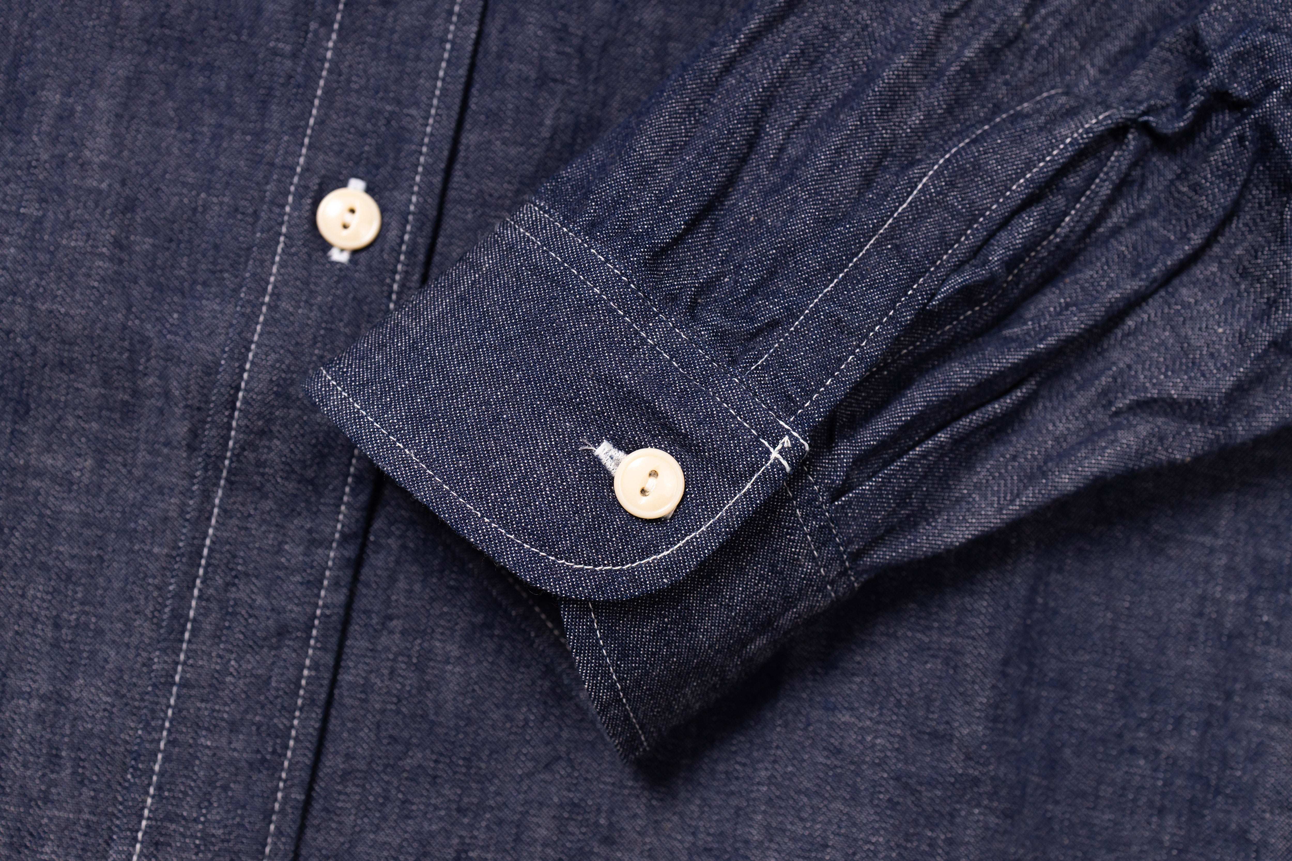 Close-up of a navy blue shirt with rolled-up sleeve and button details.