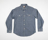 A long-sleeved chambray work shirt in indigo color, button-up front, collar, and two chest pockets.