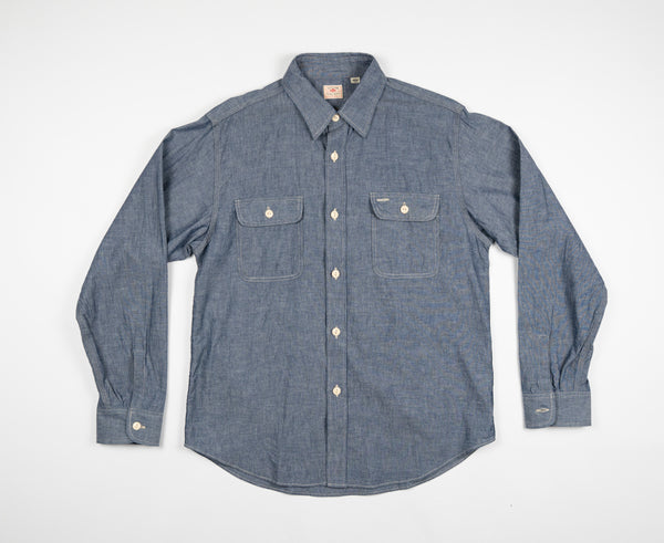 A long-sleeved chambray work shirt in indigo color, button-up front, collar, and two chest pockets.