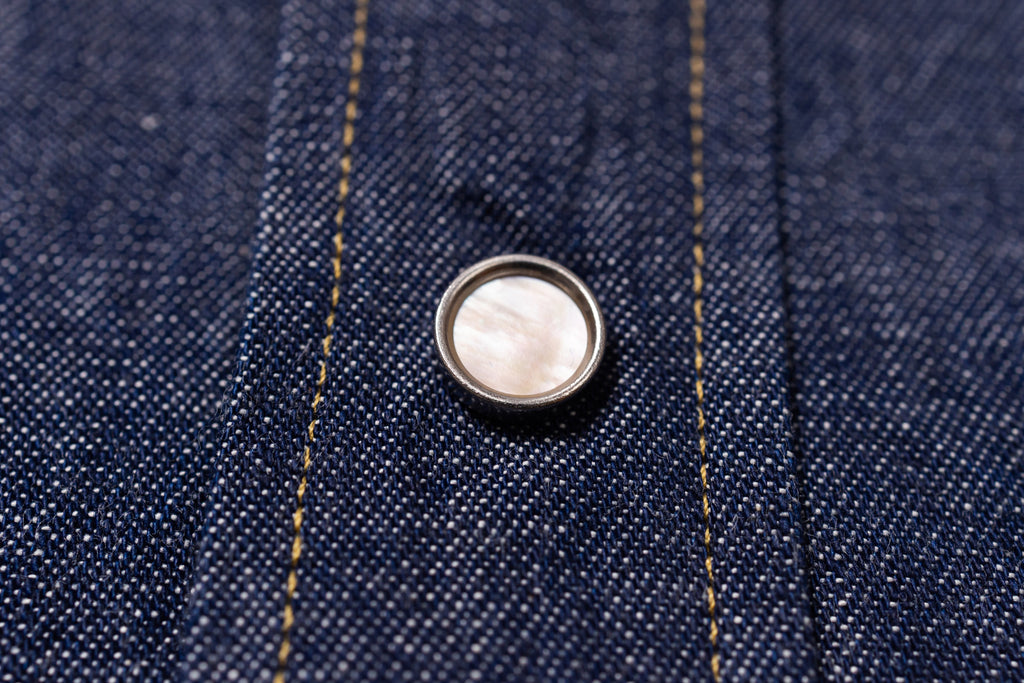 Close-up of a button on blue denim fabric