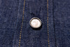 Close-up of a button on blue denim fabric
