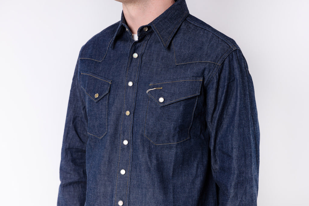 Blue denim shirt worn by a person on a white background