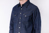 Blue denim shirt worn by a person on a white background