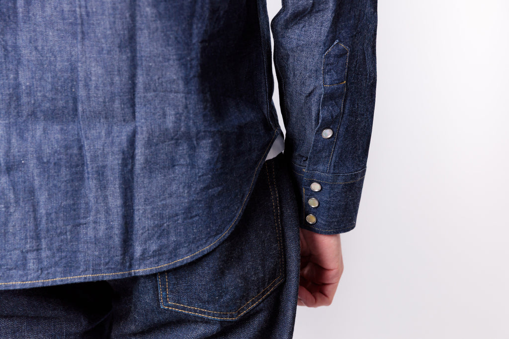 Close-up of a person wearing a blue denim shirt with buttons on a white background