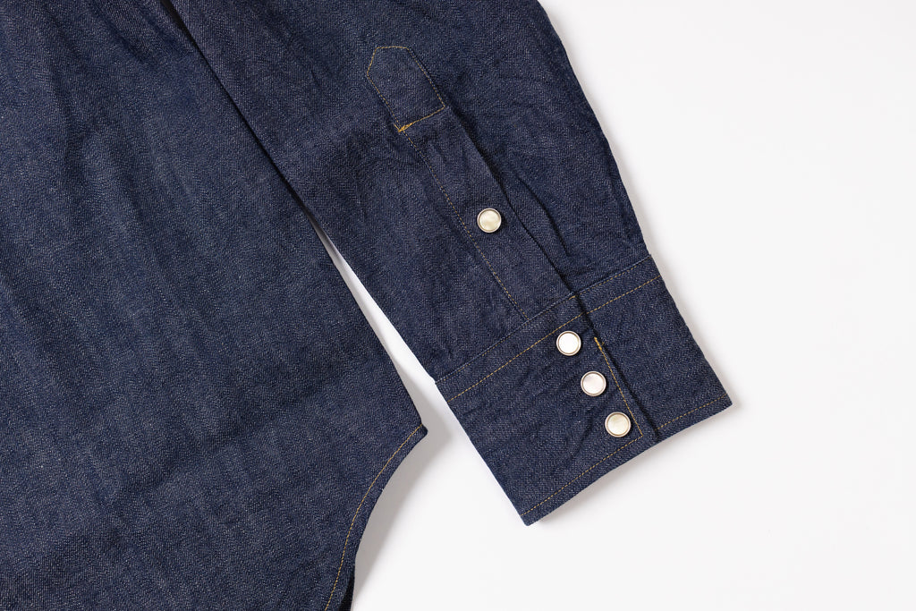 Close-up of a dark blue denim shirt with white buttons on a light gray background