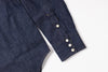 Close-up of a dark blue denim shirt with white buttons on a light gray background