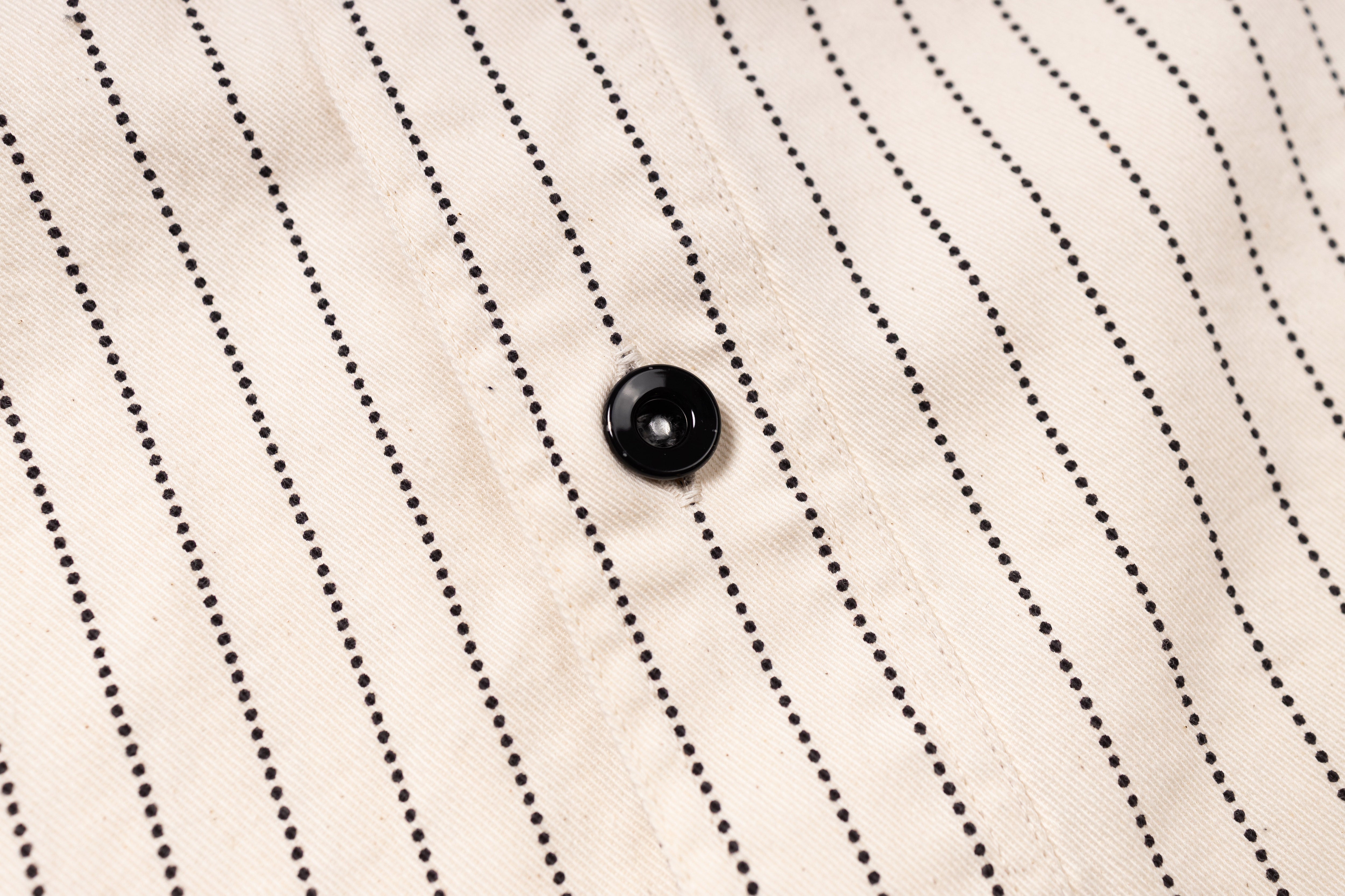 Close-up of a button on a pinstripe shirt