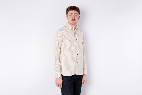 Man wearing a cream striped shirt against a white background