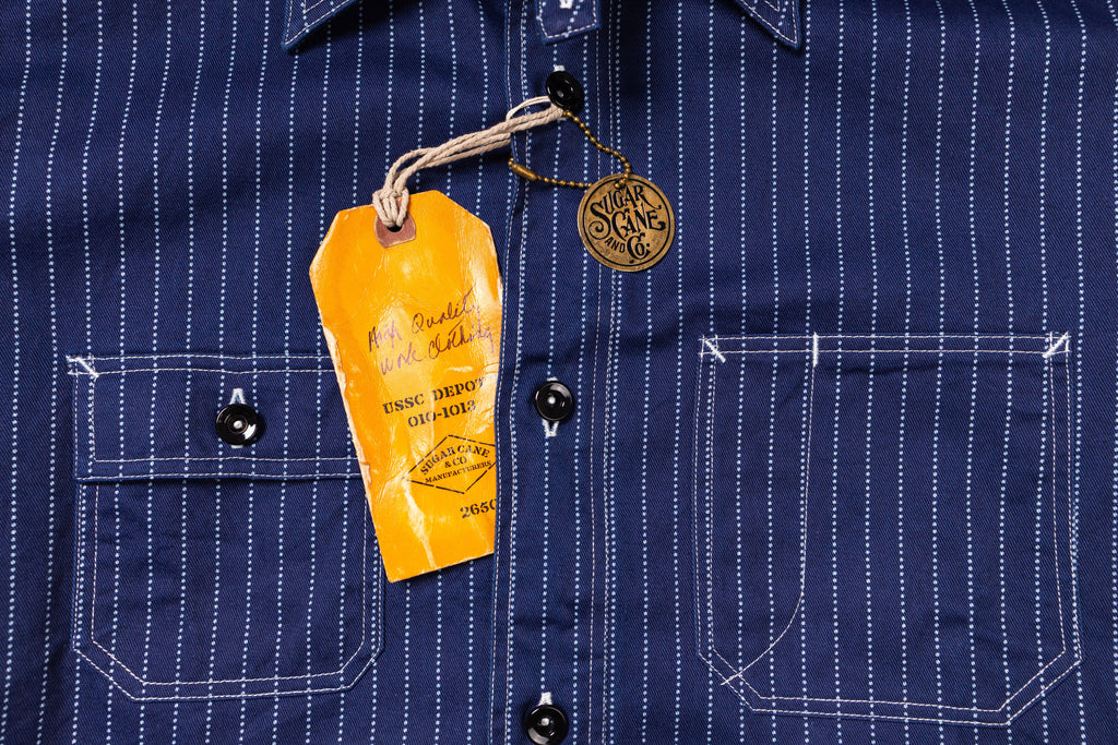 Navy pinstripe shirt with a yellow tag on a dark background