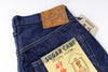 Folded blue denim jeans with a 'Sugar Cane' label on a white background