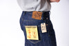 Person wearing blue jeans with a 'Sugar Cane' tag and a brown leather patch on a white background