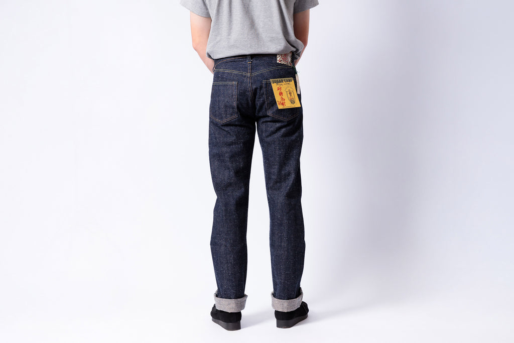 Person wearing dark blue jeans with patches on a white background