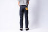 Person wearing dark blue jeans with patches on a white background