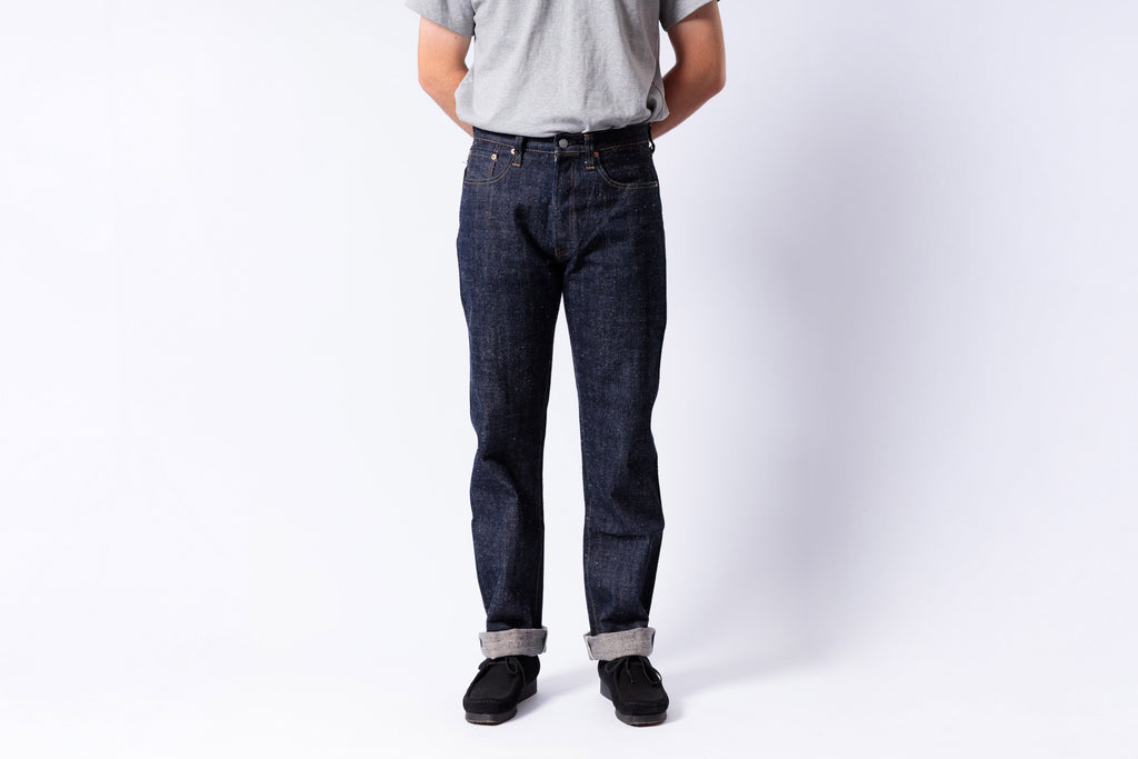 Person wearing dark blue jeans and a gray shirt on a white background