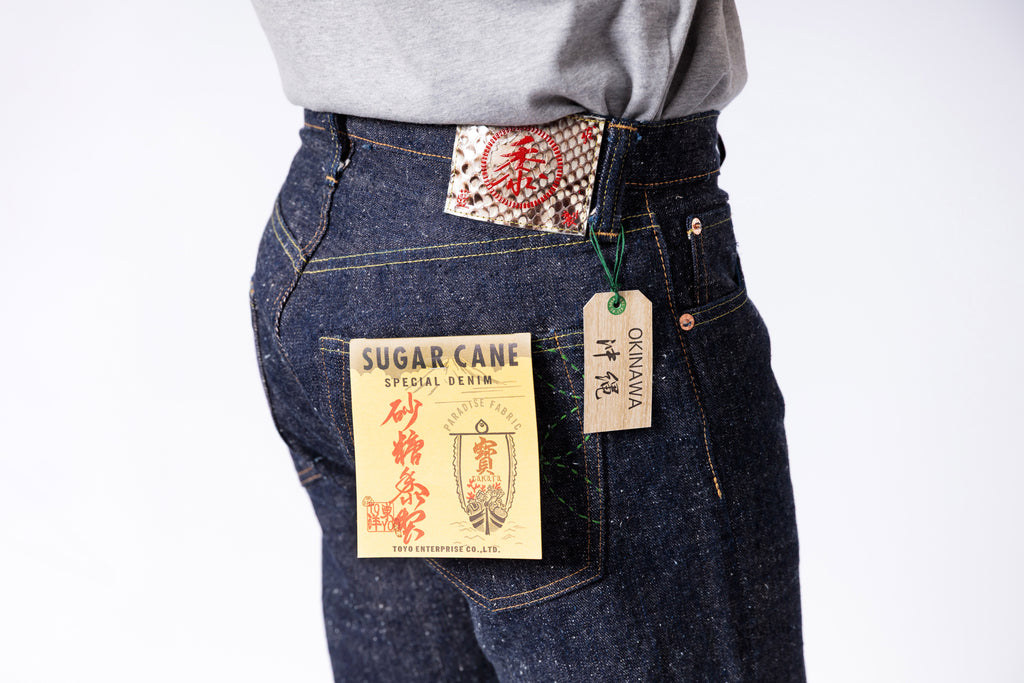 Person wearing dark blue jeans with visible brand tags on a white background
