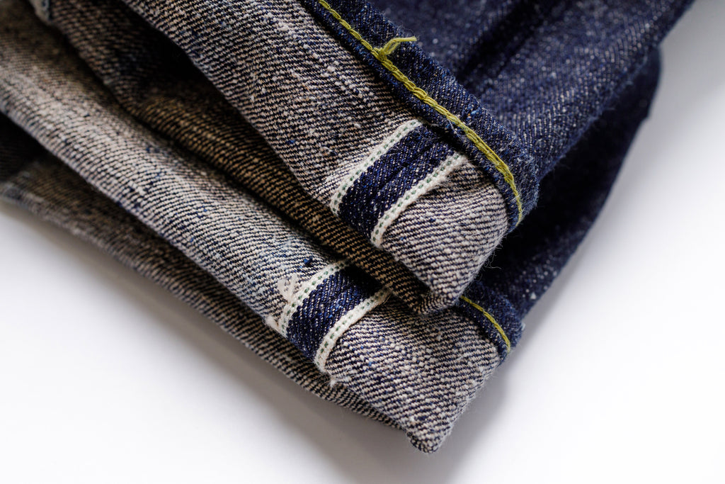 Stack of folded denim jeans on a white background