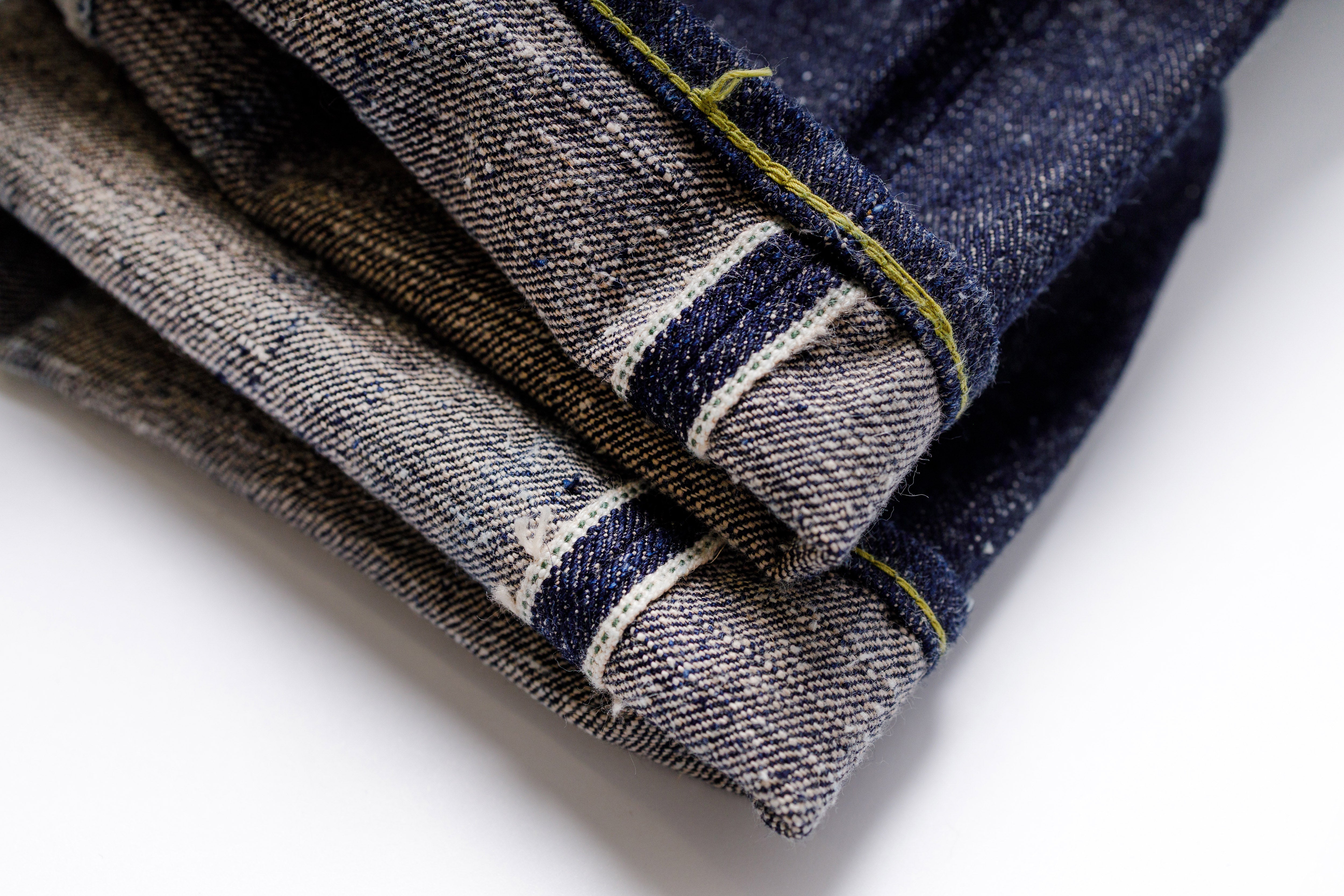 Stack of folded denim jeans on a white background