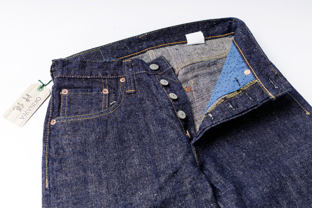 Close-up of a pair of blue jeans with a visible brand tag on a white background