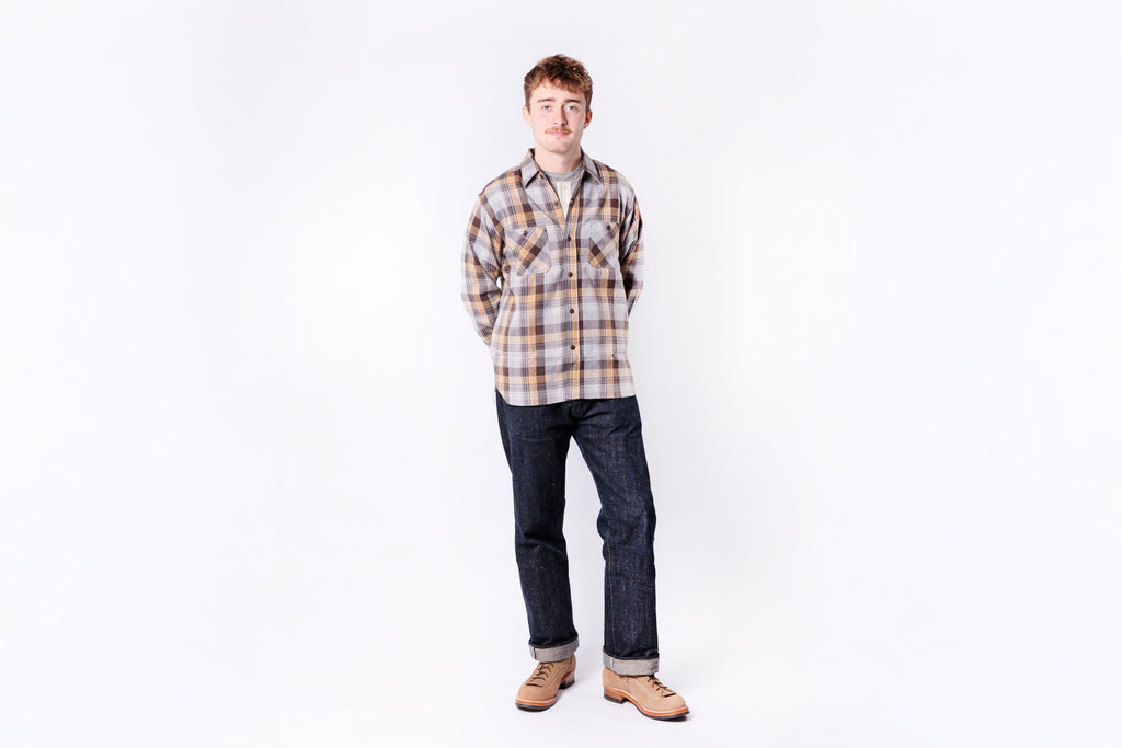 Person wearing a plaid shirt and jeans on a white background