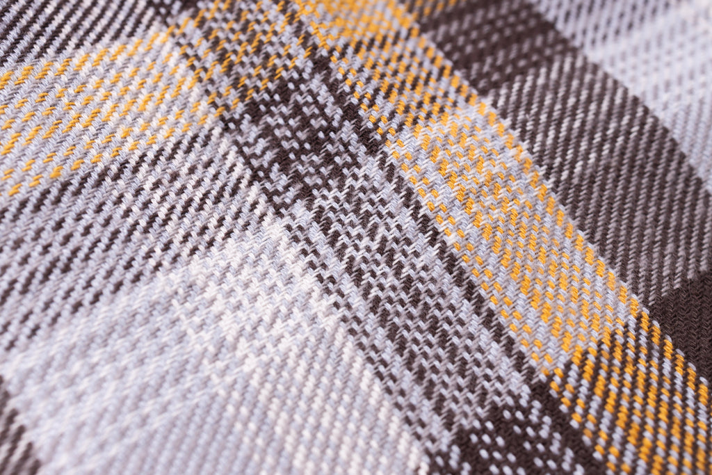 Close-up of a plaid fabric with brown, yellow, and gray colors.