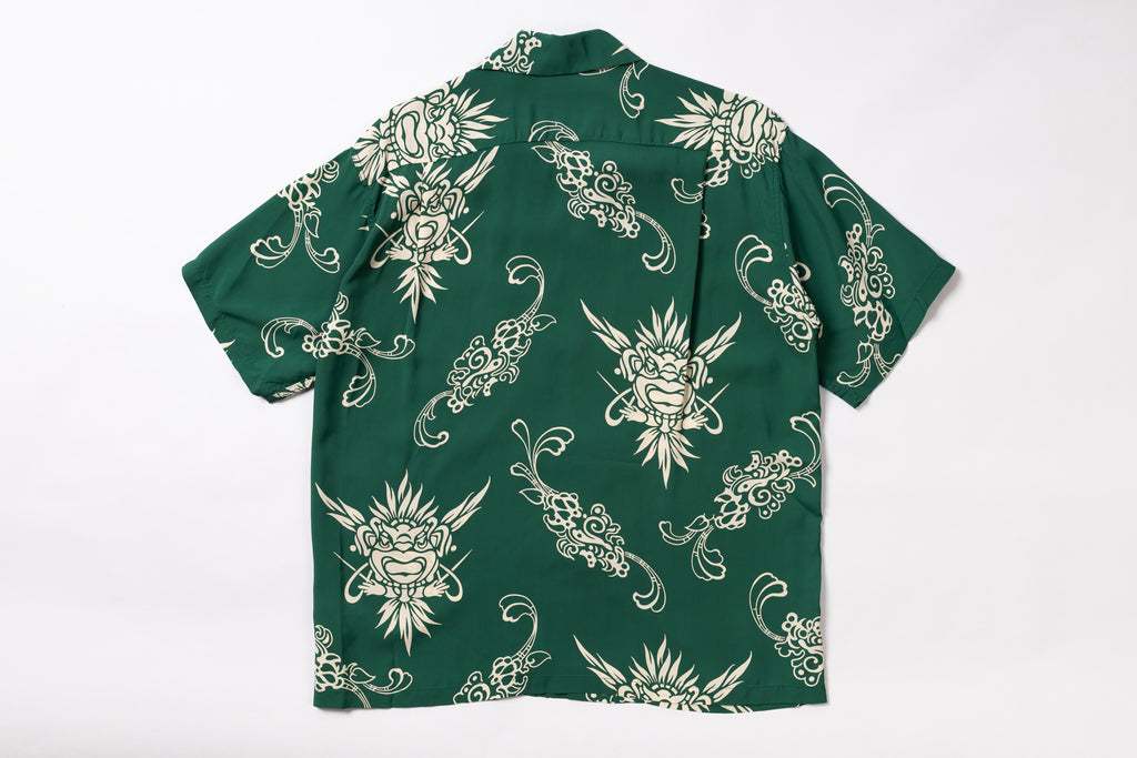 A green short-sleeve button-up shirt with a repeating cream-colored tattoo-style dragon and floral pattern, laid flat against a white background.