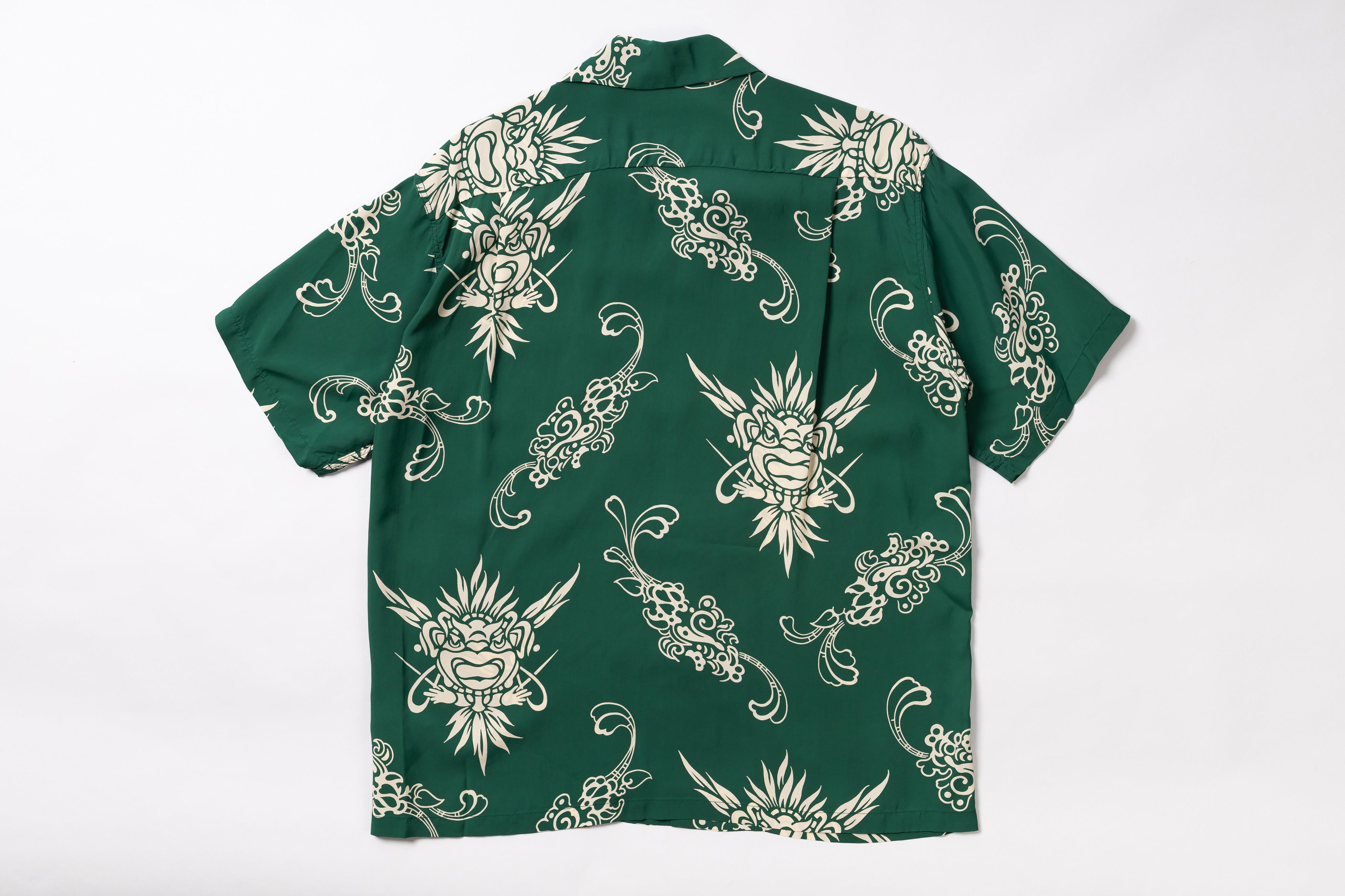A green short-sleeve button-up shirt with a repeating cream-colored tattoo-style dragon and floral pattern, laid flat against a white background.