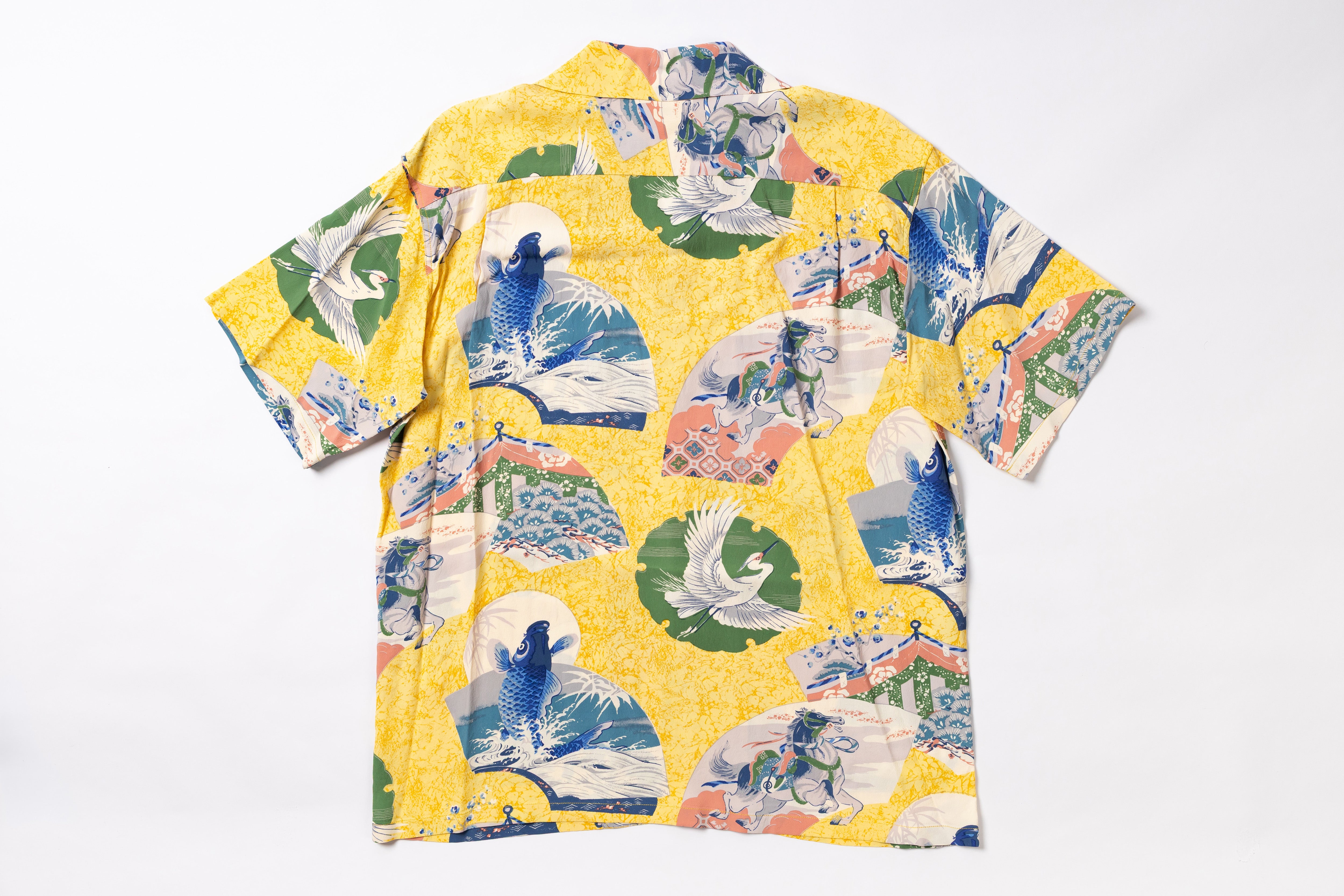A yellow short-sleeve button-up shirt with a Japanese wave and koi fish print, laid flat on a white background.