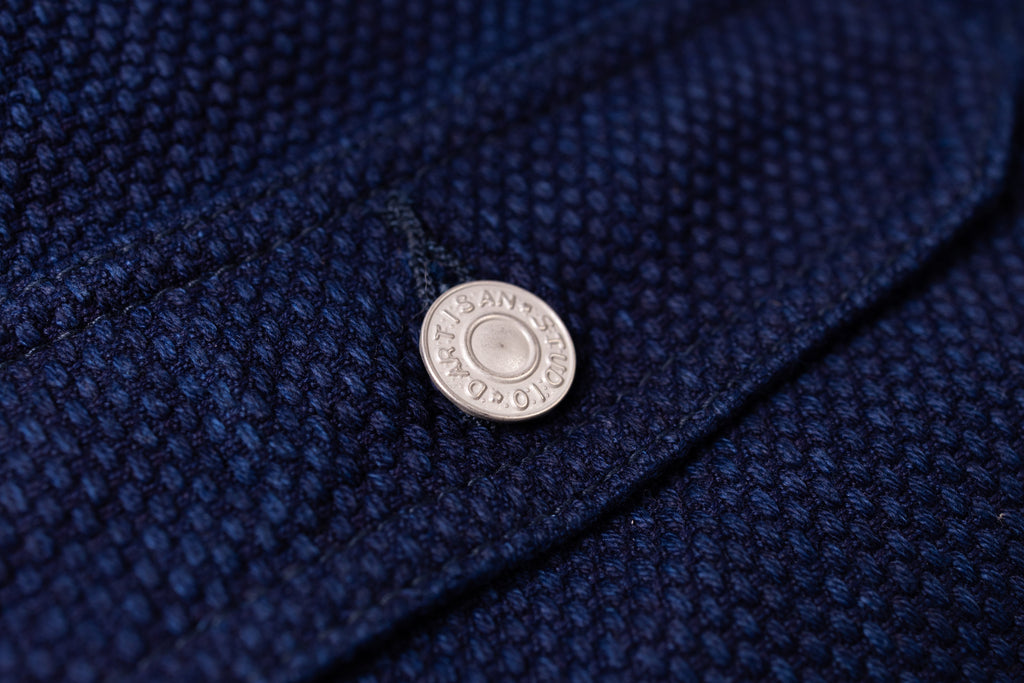 Close-up of a button on a textured blue fabric