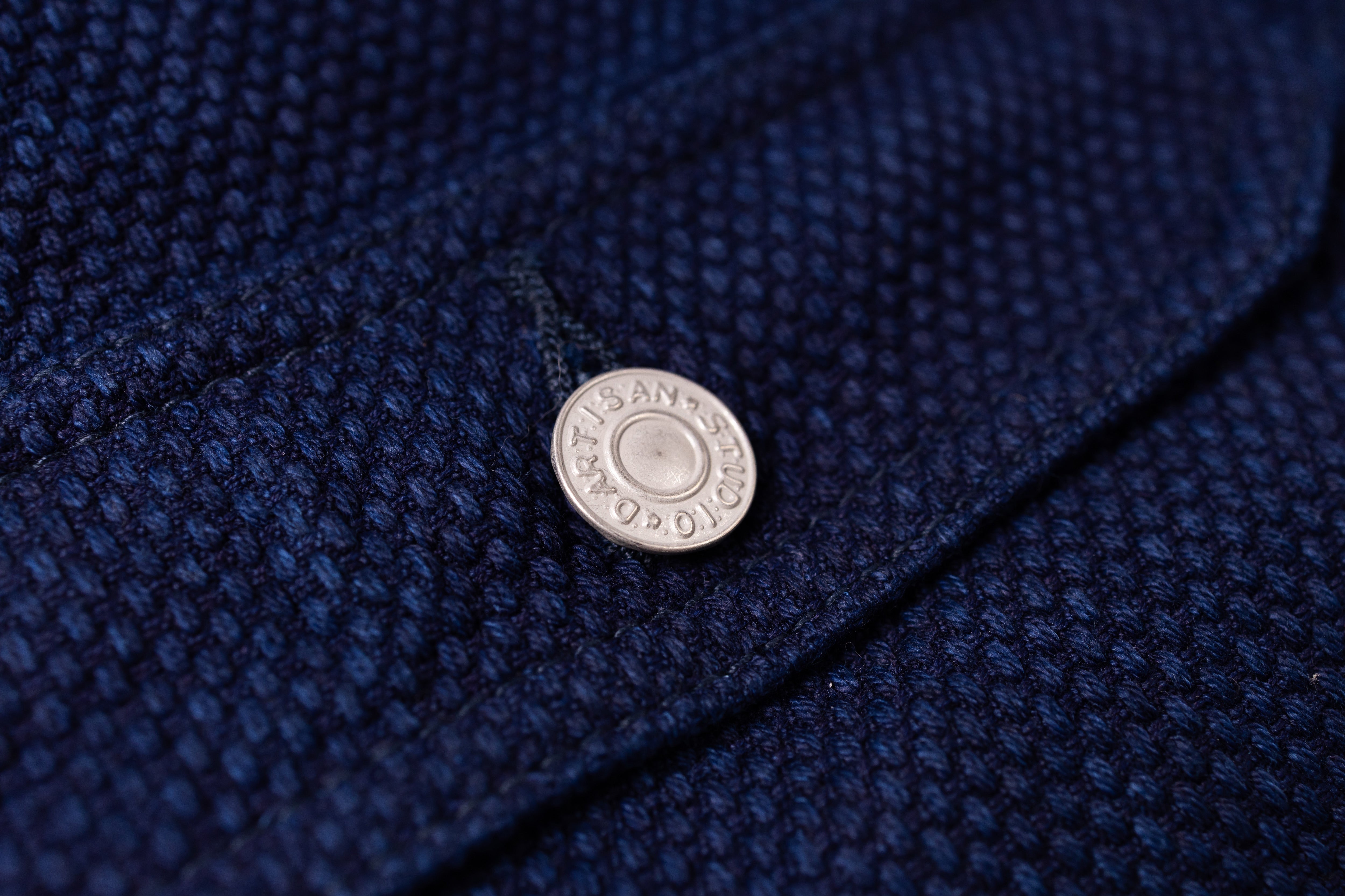 Close-up of a button on a textured blue fabric