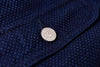 Close-up of a button on a textured blue fabric