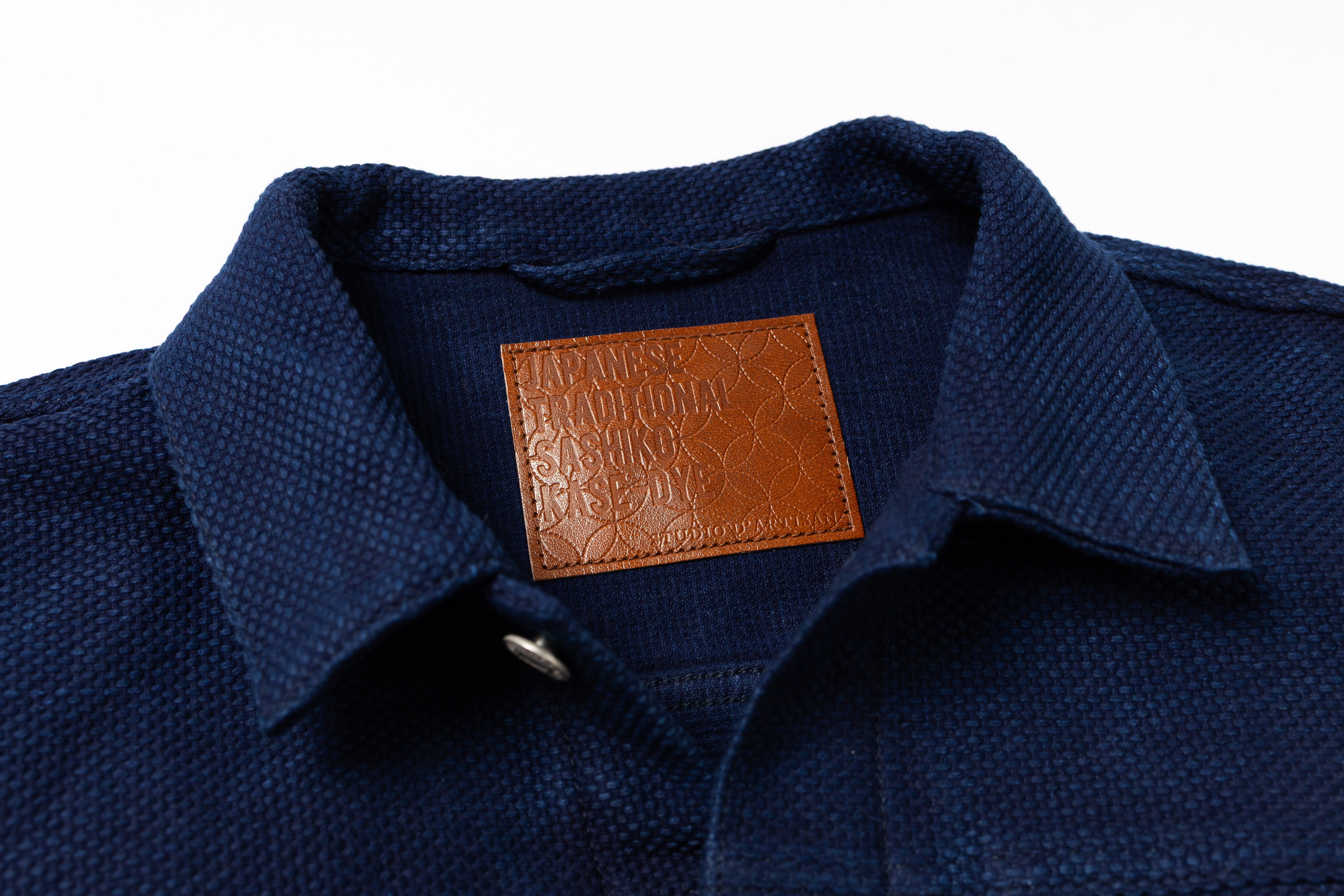 Navy blue shirt with a brown leather label on a white background
