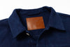 Navy blue shirt with a brown leather label on a white background