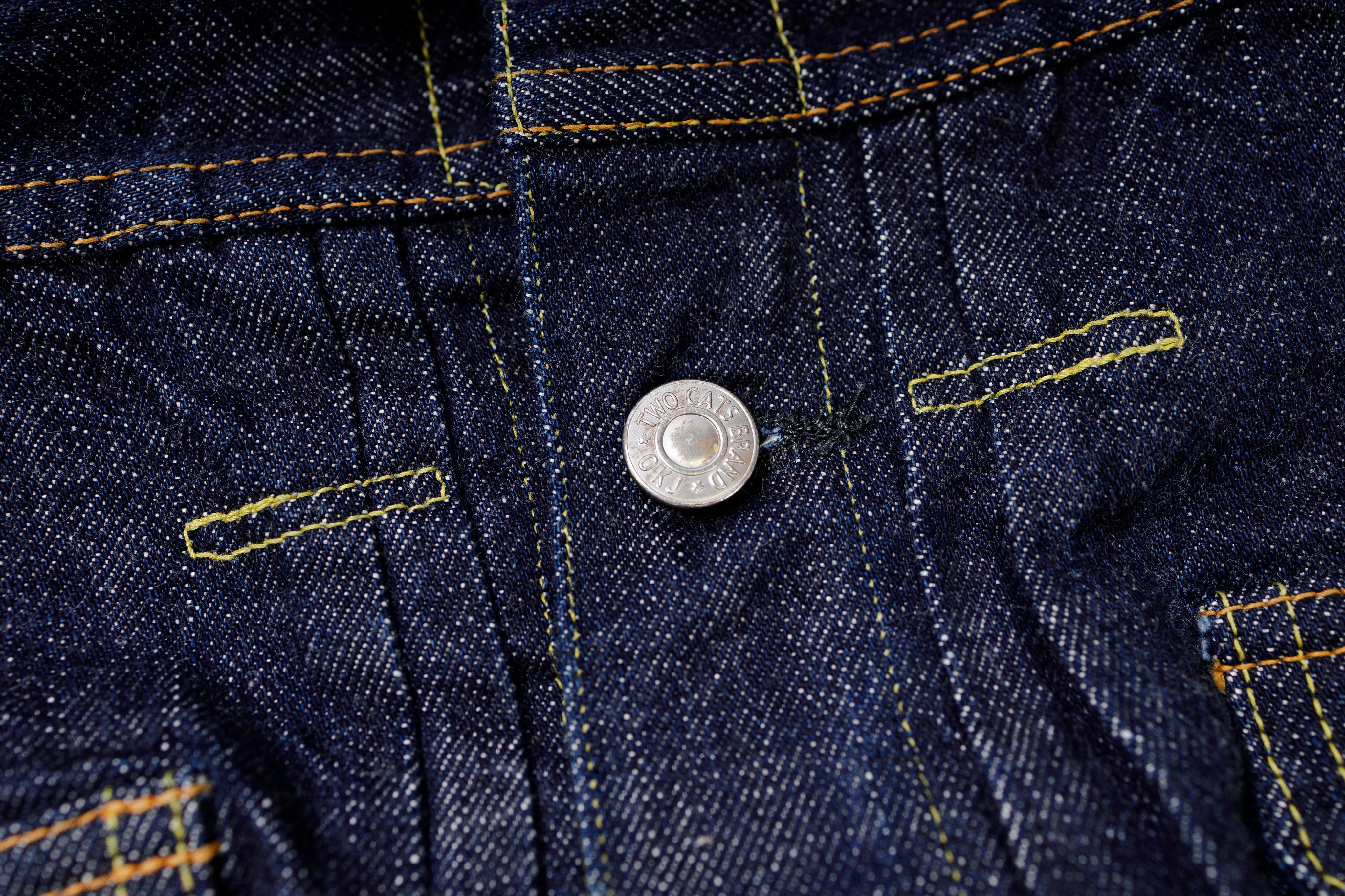 Close-up of a button on a denim fabric with stitching details.
