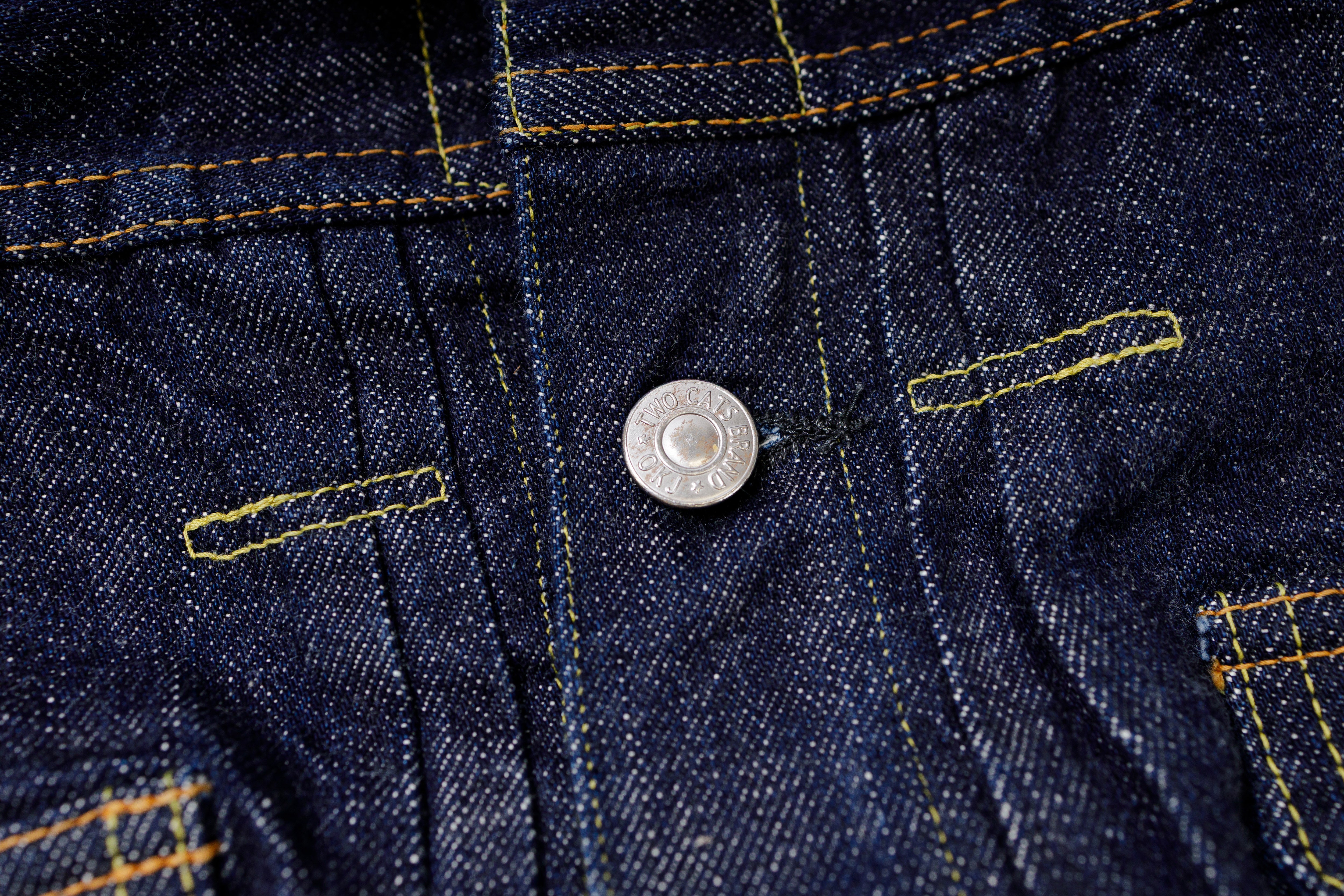 Close-up of a button on a denim fabric with stitching details.