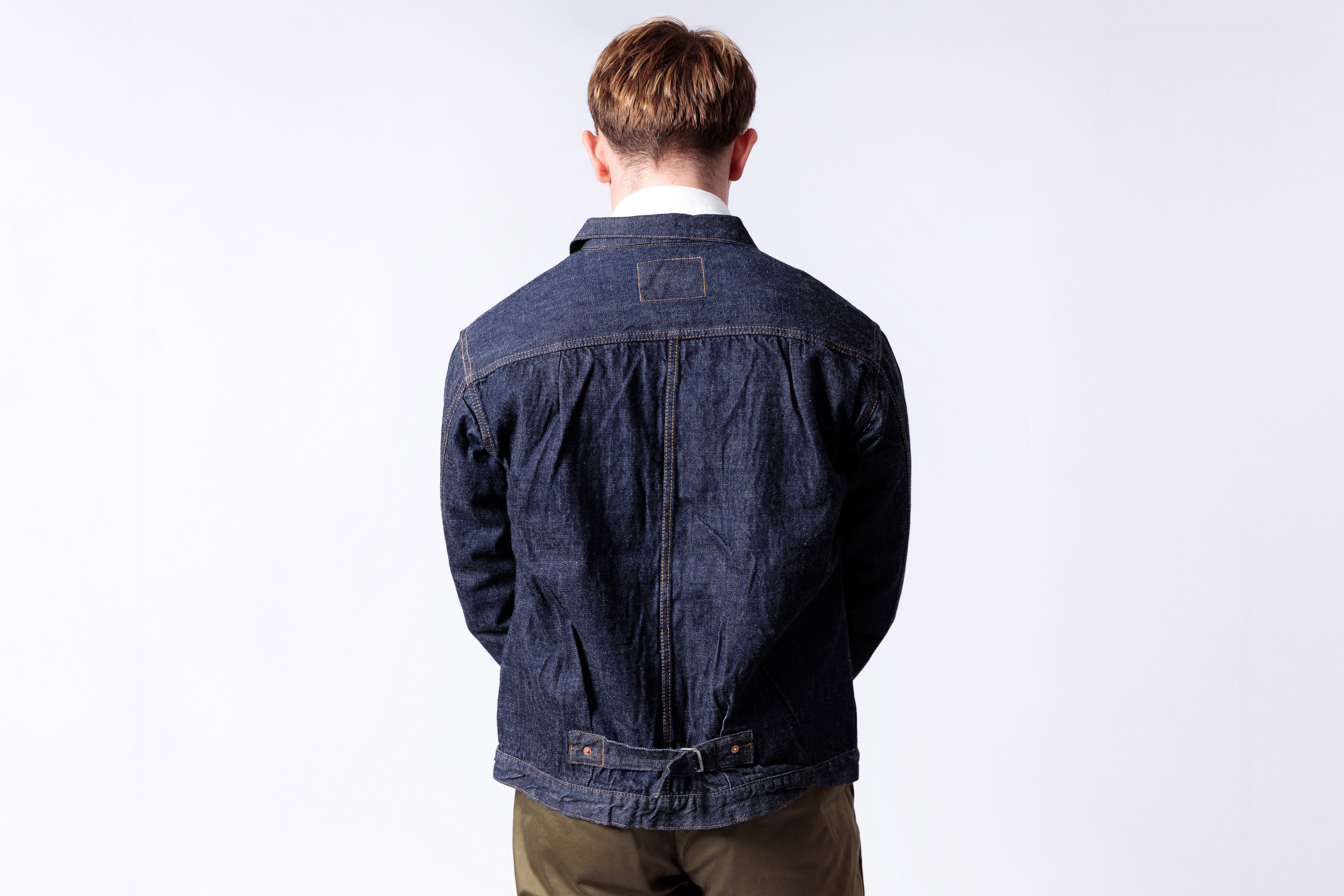 Person wearing a blue denim jacket on a white background