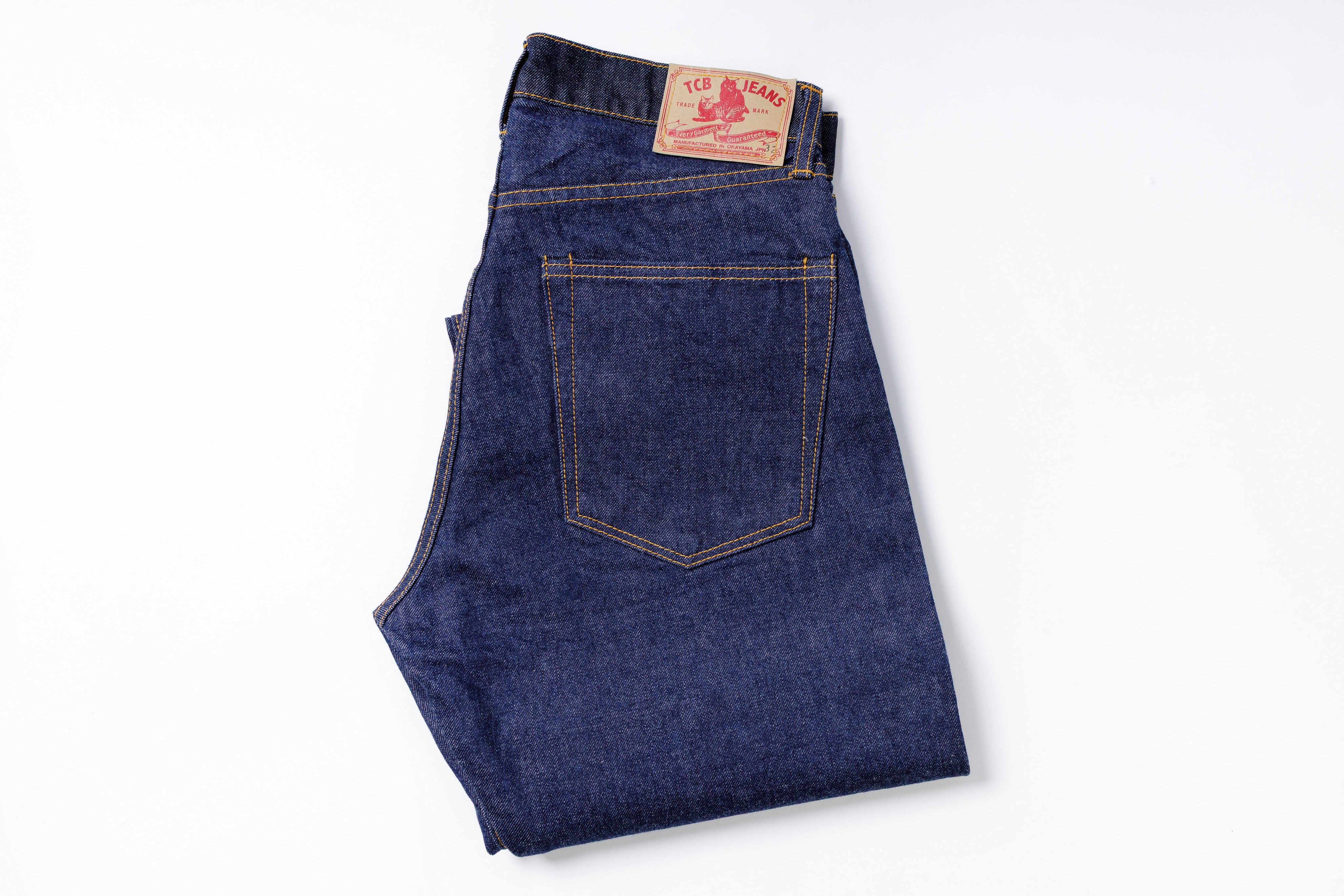 Folded pair of blue jeans with a brand label on a white background
