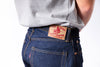 Person wearing blue jeans with a brand label on a white background