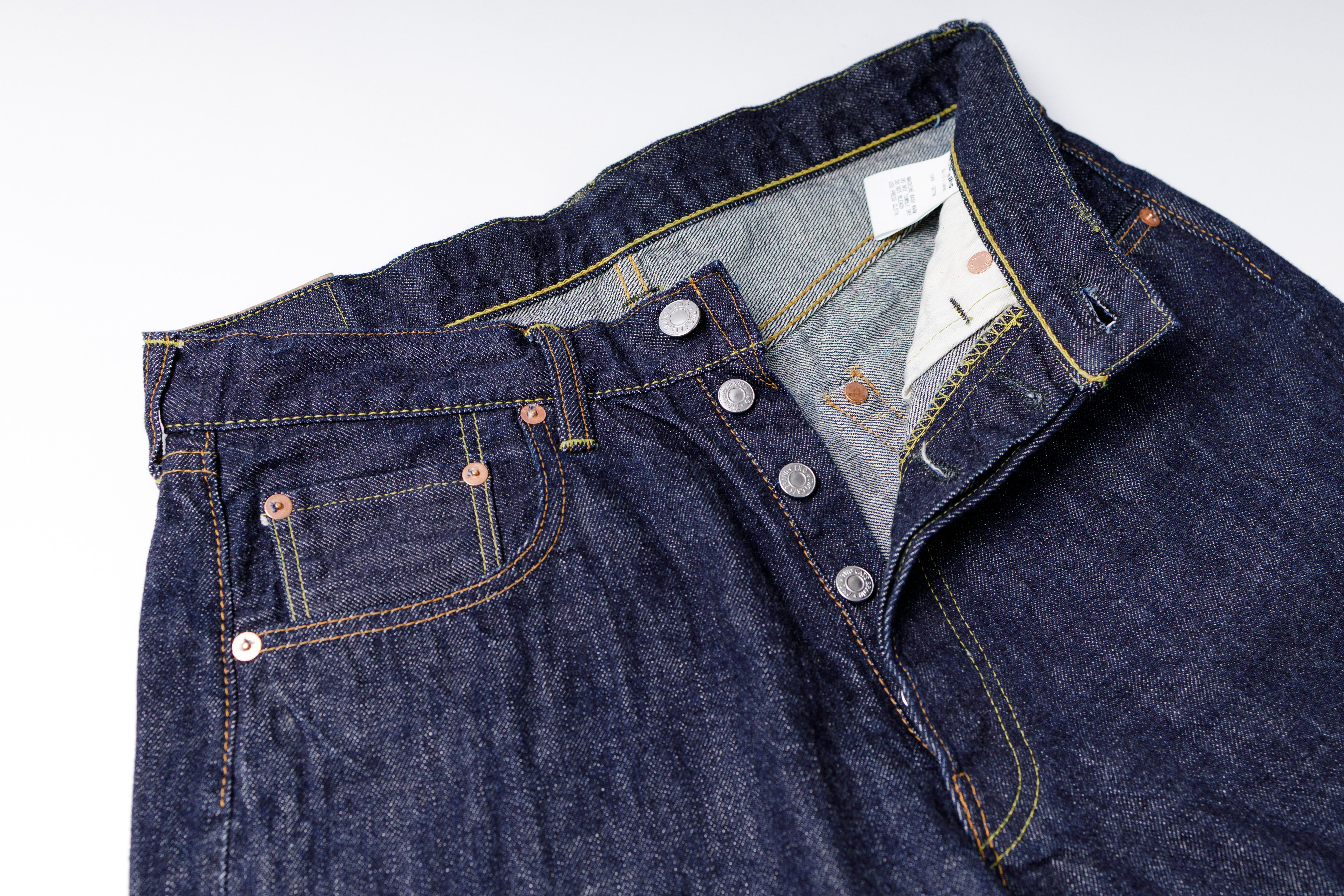 Close-up of a blue denim jacket with a white label on a light gray background