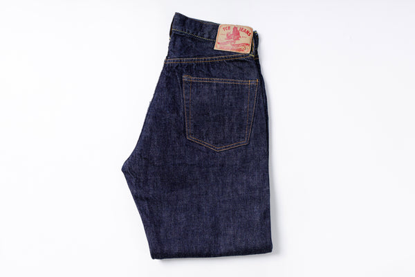 Folded pair of blue jeans with a brand label on a white background