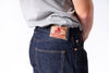 Person wearing blue jeans with a brand label on a white background