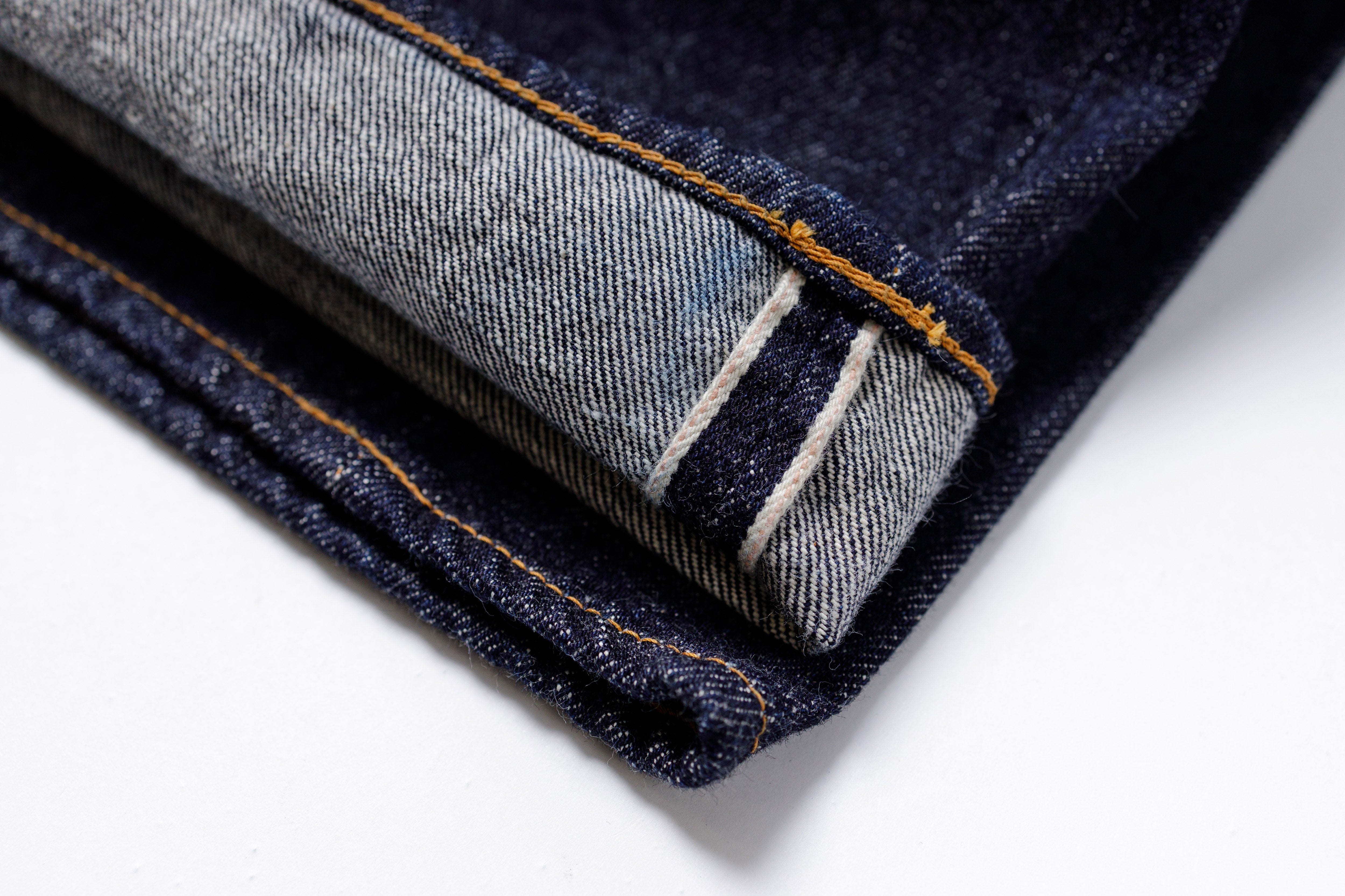 Close-up of folded denim jeans with visible stitching on a white background