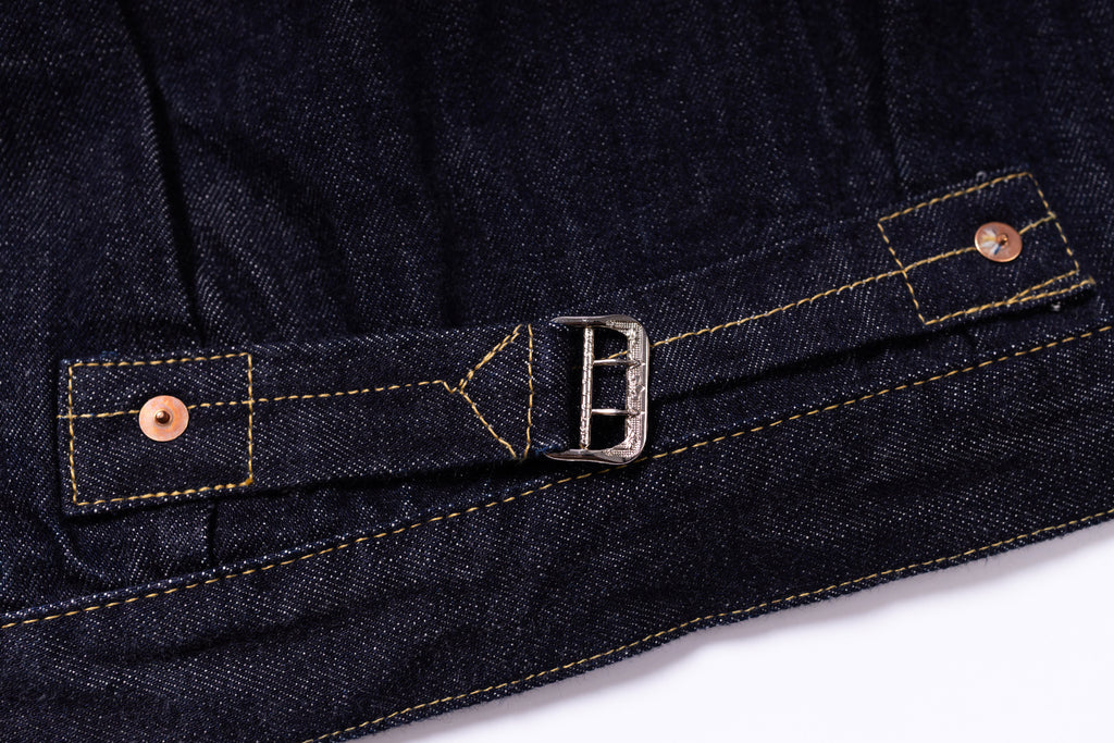 Close-up of dark denim fabric with a buckle and buttons on a white background